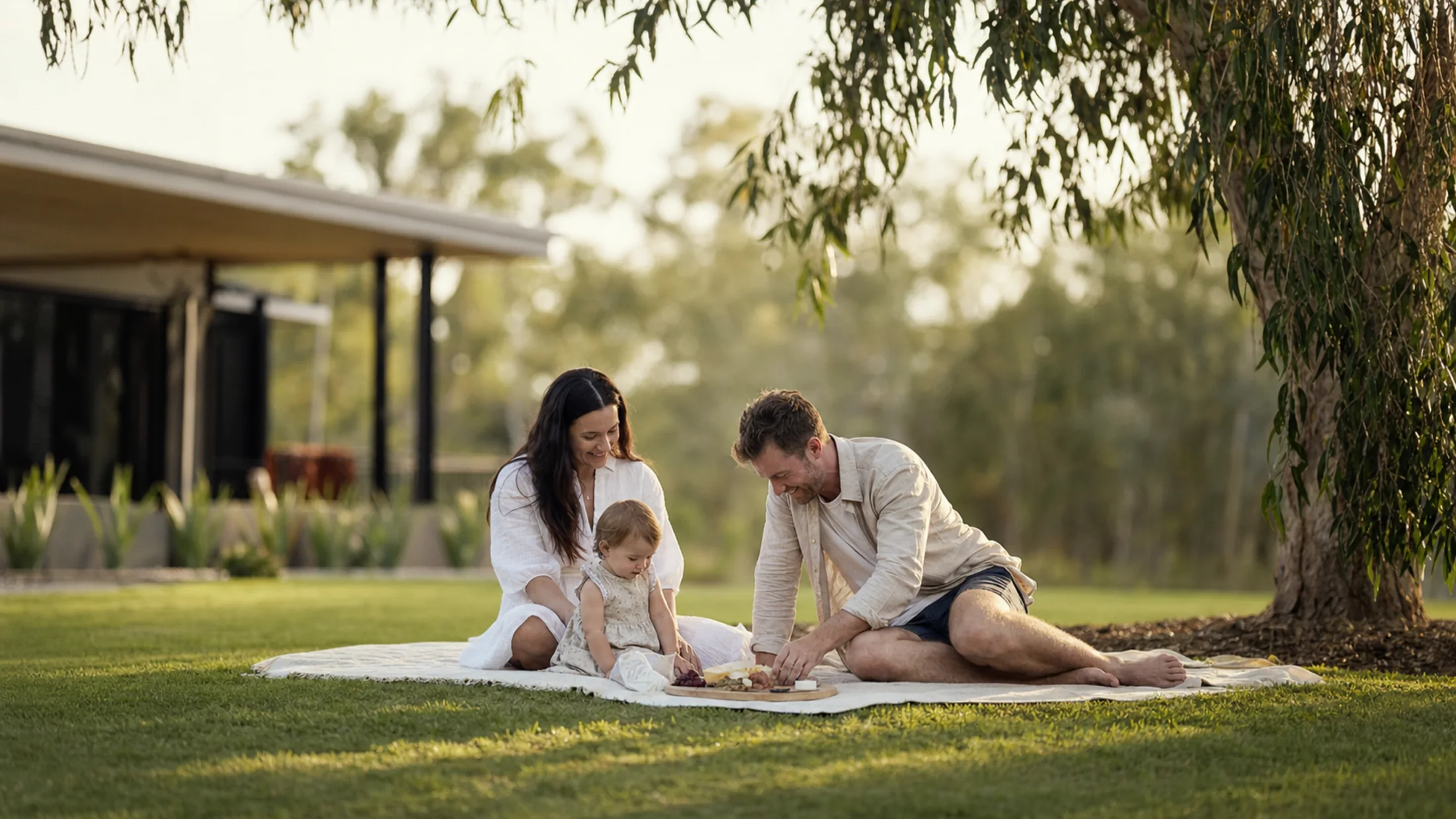 A young family relaxing on a picnic rug on the lawn